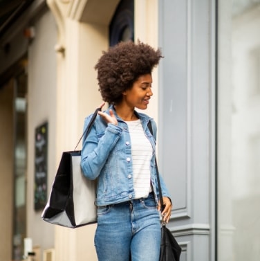 woman with shopping bags strolling by storefronts
